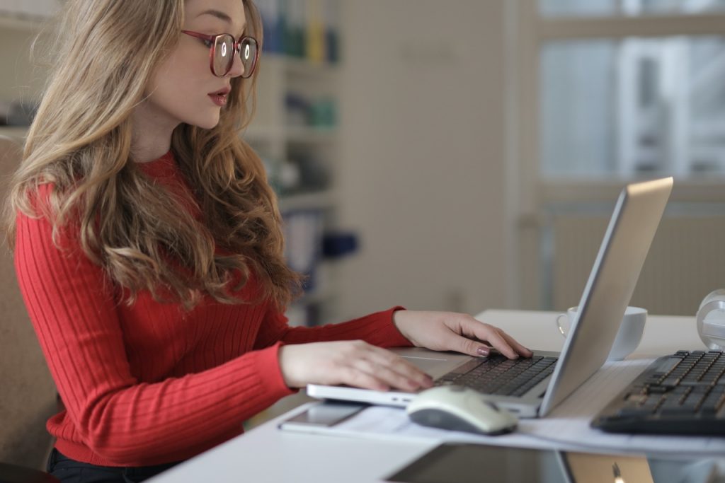  A young freelancer wearing glasses works on her laptop while feeling stressed and isolated.