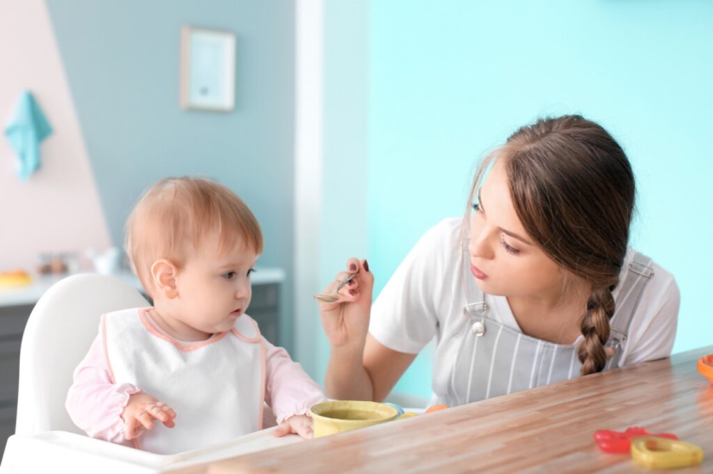 A babysitter feeding a baby